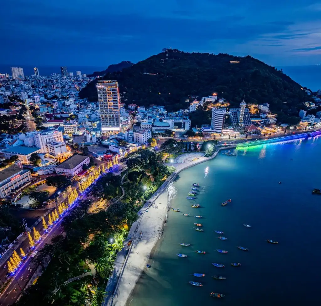 A breathtaking aerial view of a coastal city with vibrant lights at dusk.